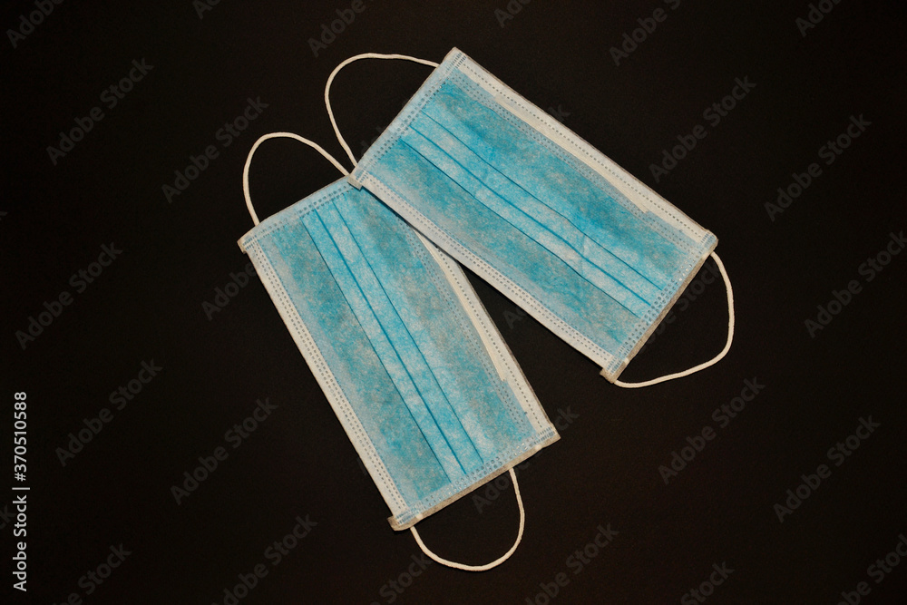 Pair of blue disposable medical respiratory masks on a black background Pair of blue disposable medical respiratory masks on a black background