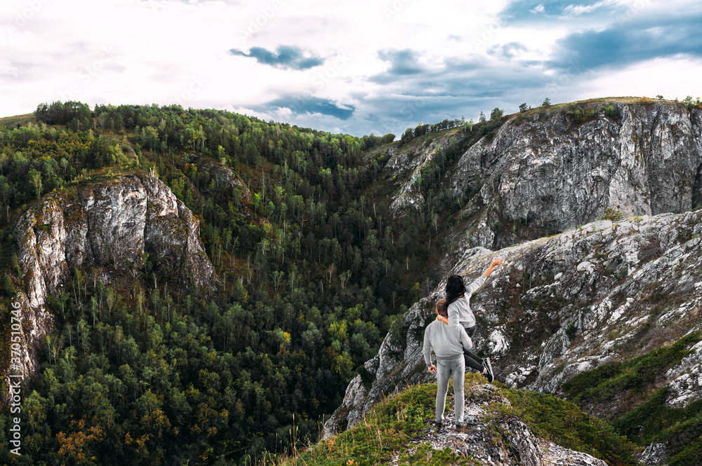 Beautiful couple among the mountains. A couple in love in the mountains, back view. The man lifted the woman into his arms. The couple travels among the mountains. Hiking in the mountains. Copy space