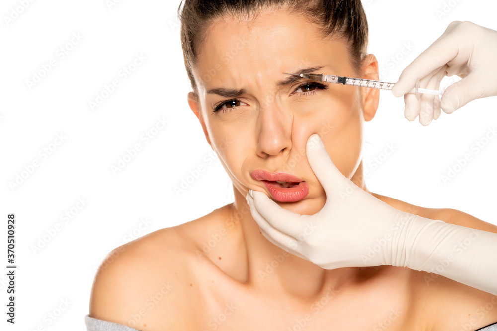 Portrait of a young frightened woman on a face filler injection procedure