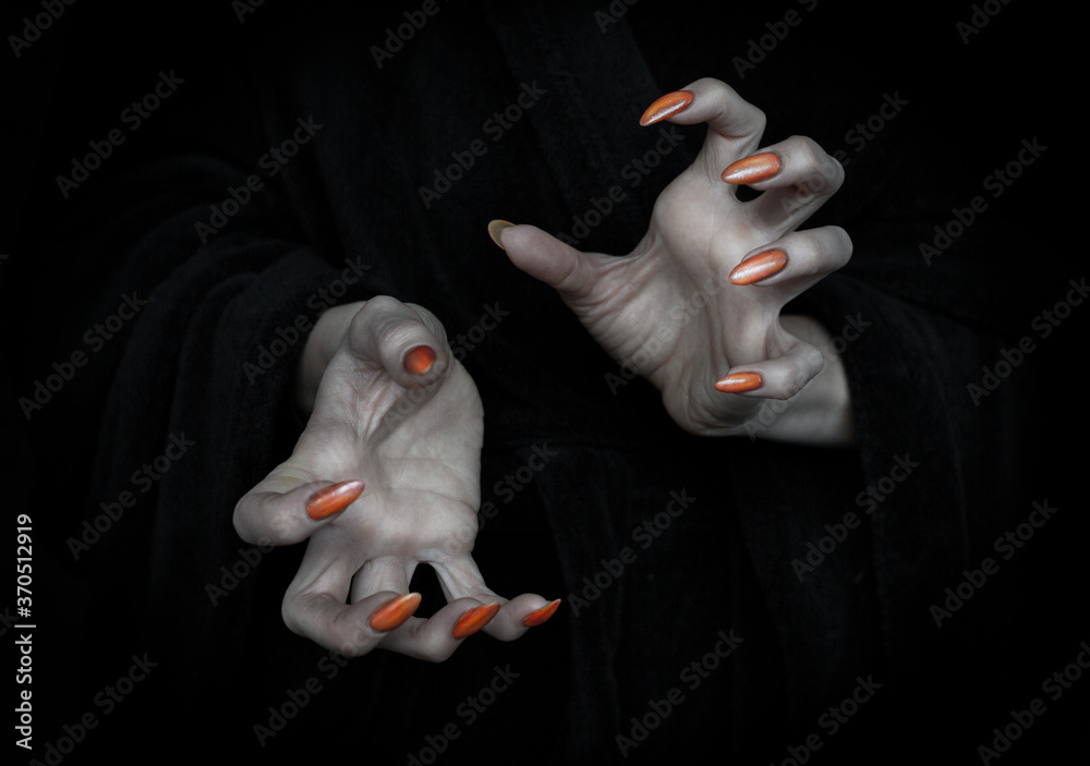 Vampire hands with sharp claws and knobby fingers in the dark, close up