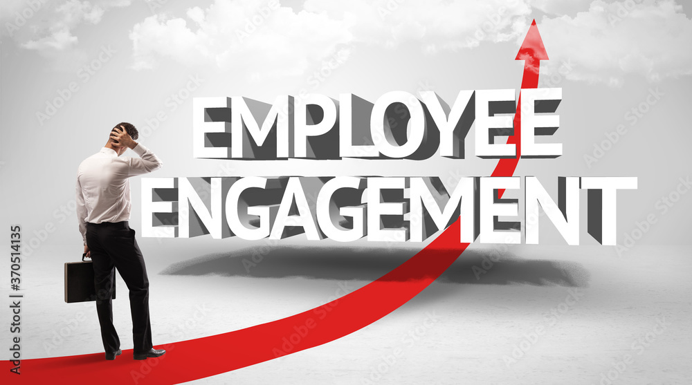 Rear view of a businessman standing in front of EMPLOYEE ENGAGEMENT inscription, successful business concept Rear view of a businessman standing in front of EMPLOYEE ENGAGEMENT inscription, successful business concept