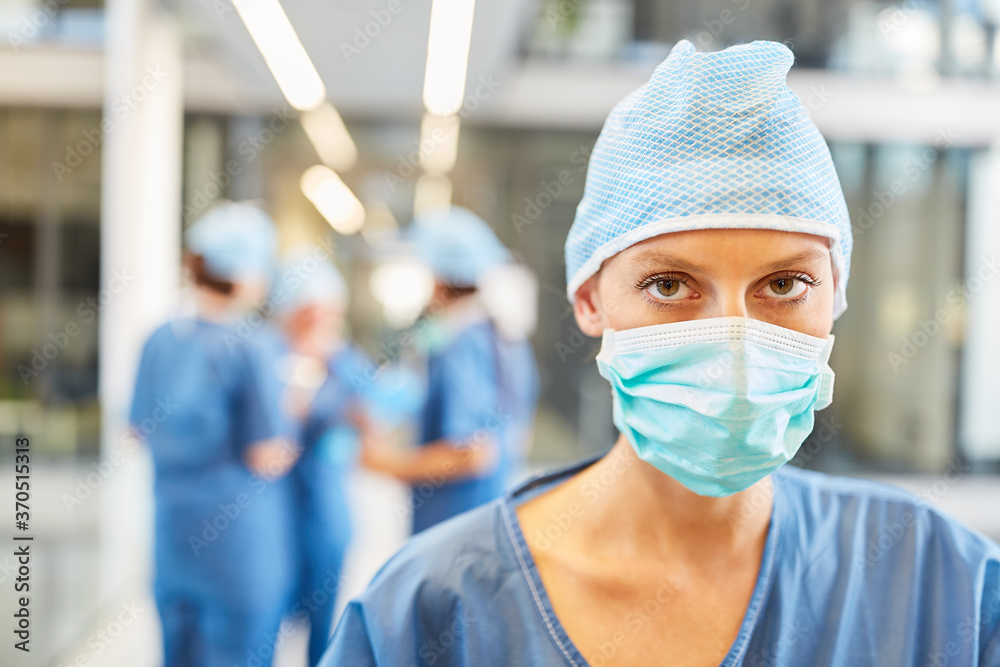 Junge Frau als Chirurgin in blauer OP-Kleidung - obrazy, fototapety, plakaty 