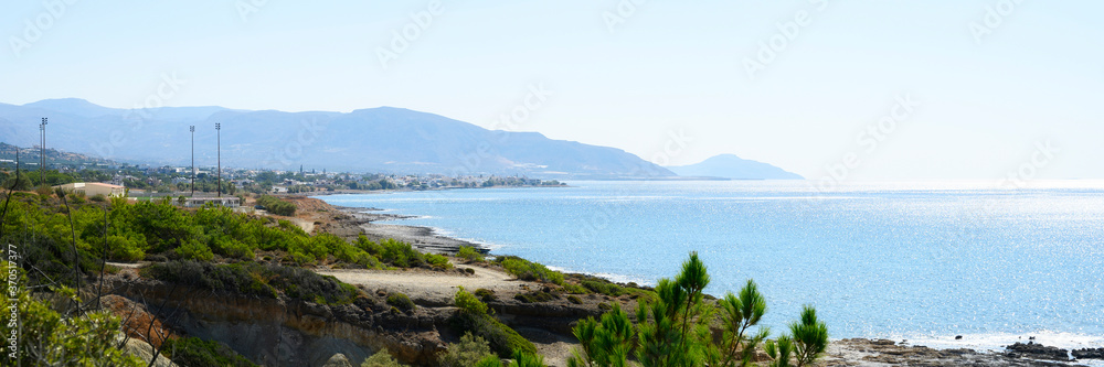 beautiful blue lagoon with clear sea water and a pebble beach and rocks, deserted, with a view of the city in the distance. banner