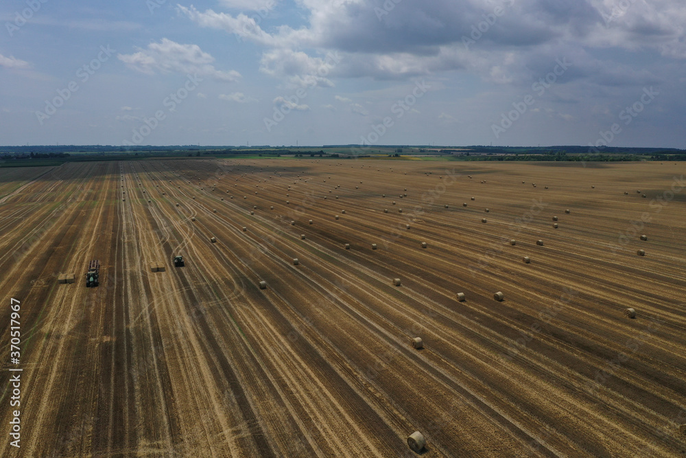 Agricultural field made of yellow round round big bales after harvest, straw rolls, straw bales in the agricultural field. Hay collection in the summer field. Drone photo in Úri, Hungary - 03/07/2020
