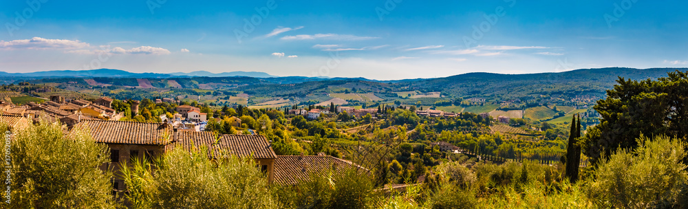Beautiful panorama picture of the famous medieval town San Gimignano and the lovely countryside. A typical Tuscan landscape with its valleys on a hot sunny day with a blue sky.