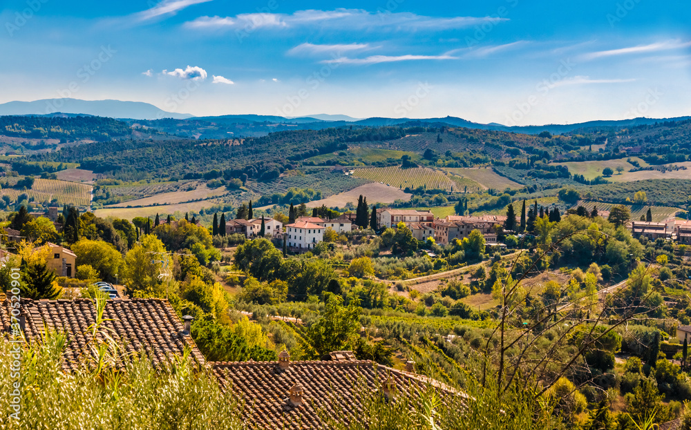 Beautiful panoramic view of the lovely countryside of the famous medieval hill town San Gimignano, a typical Tuscan landscape with its valleys on a hot sunny day with a blue sky.