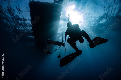silhouette of scuba diver underwater in ocean under boat