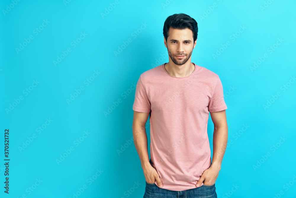 Young handsome man portrait wearing pink t-shirt looking at camera on blue background Young handsome man portrait wearing pink t-shirt looking at camera on blue background
