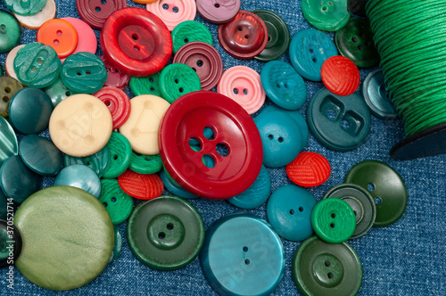 multi colored buttons and thread skein on denim. background