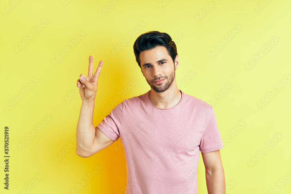 Young handsome man show victory sign on yellow background Young handsome man show victory sign on yellow background