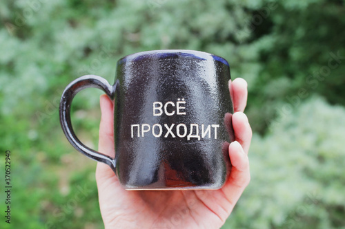 black cup with an inscription in Russian: Everything passes. the words of King Solomon from the ancient parable about the ring. All will pass. photo