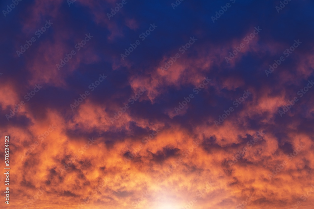 Brightly fiery sunset. Picturesque red clouds on a blue sky