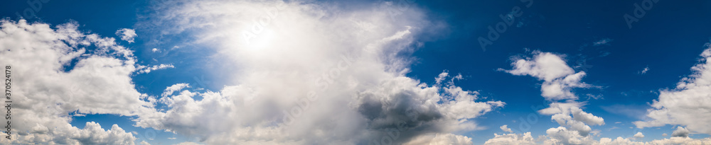 White fluffy cumulus clouds in deep blue azure sunshine sky. Summer good weather, climate, eco, nature beauty concept sky ultra wide high resolution panoramic background.
