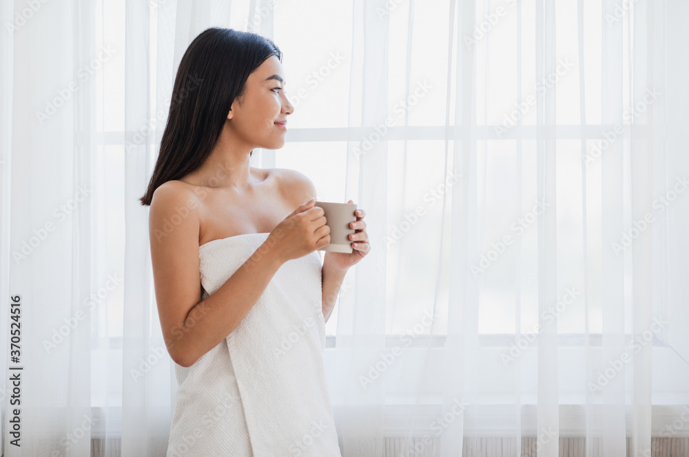 Dreamy girl with cup of morning coffee looking through window Dreamy girl with cup of morning coffee looking through window