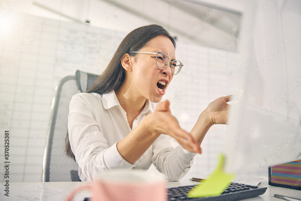 Emotional brunette woman shouting at her computer