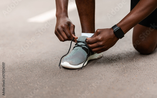 Closeup of black guy tying his shoelaces before jogging