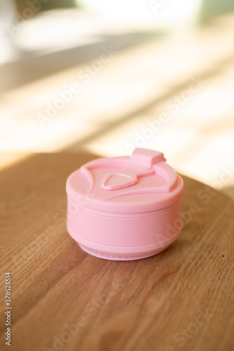 Pink foldable silicone cup for drinks without plastic in the style of zero waste on a interior background, close-up. Product photography. Store content