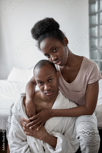 portrait of beautiful african black couple at home, man and woman posing at camera, sit on bed. in love