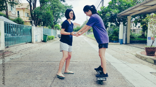 Two Asian girl practicing wave board middle of the road