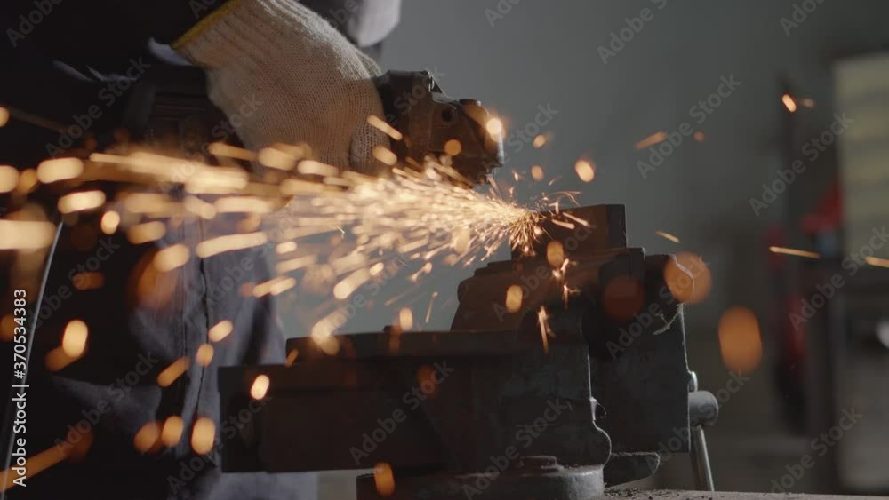 Hand of worker with grinder metal and orange flying sparks close up
