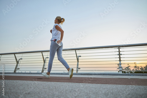 Woman jogging with a plastic bottle in her hand