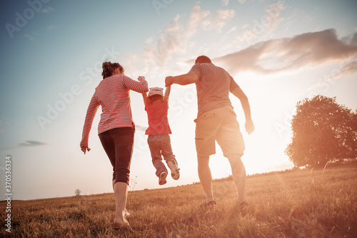 girl with mother and father holding hands on the nature