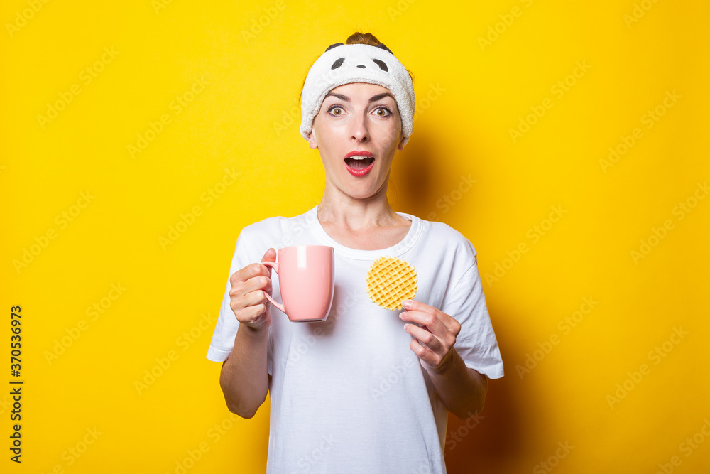 Surprised young woman with a cup of coffee and a Belgian waffle on a yellow background Surprised young woman with a cup of coffee and a Belgian waffle on a yellow background