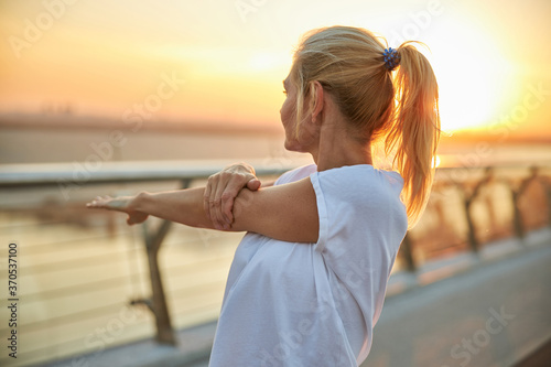 Foto Female in a t-shirt doing a shoulder stretch