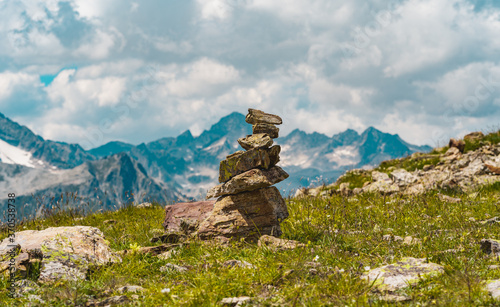 Close up of pile of stones on ground against mountain landscape. Decoration of stones on top of mountain on summer day. © Anton Dios