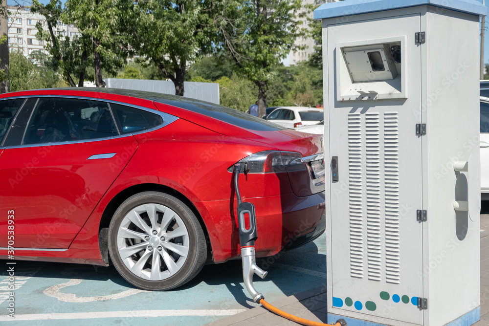 Electric car charging on parking lot with electric car charging station