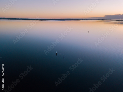 Aerial view of three poles in the middle of lake at dawn.
