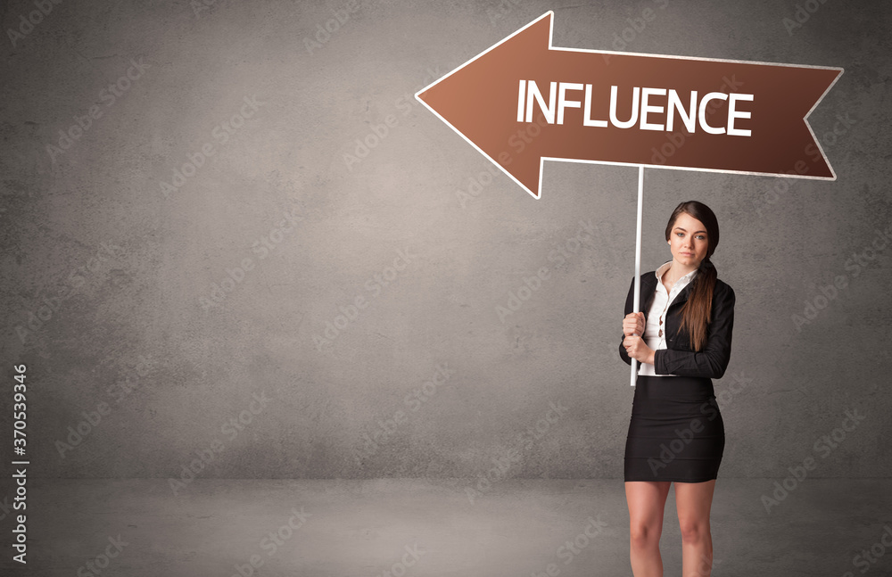 Young business person in casual holding road sign with INFLUENCE inscription, business direction concept Young business person in casual holding road sign with INFLUENCE inscription, business direction concept