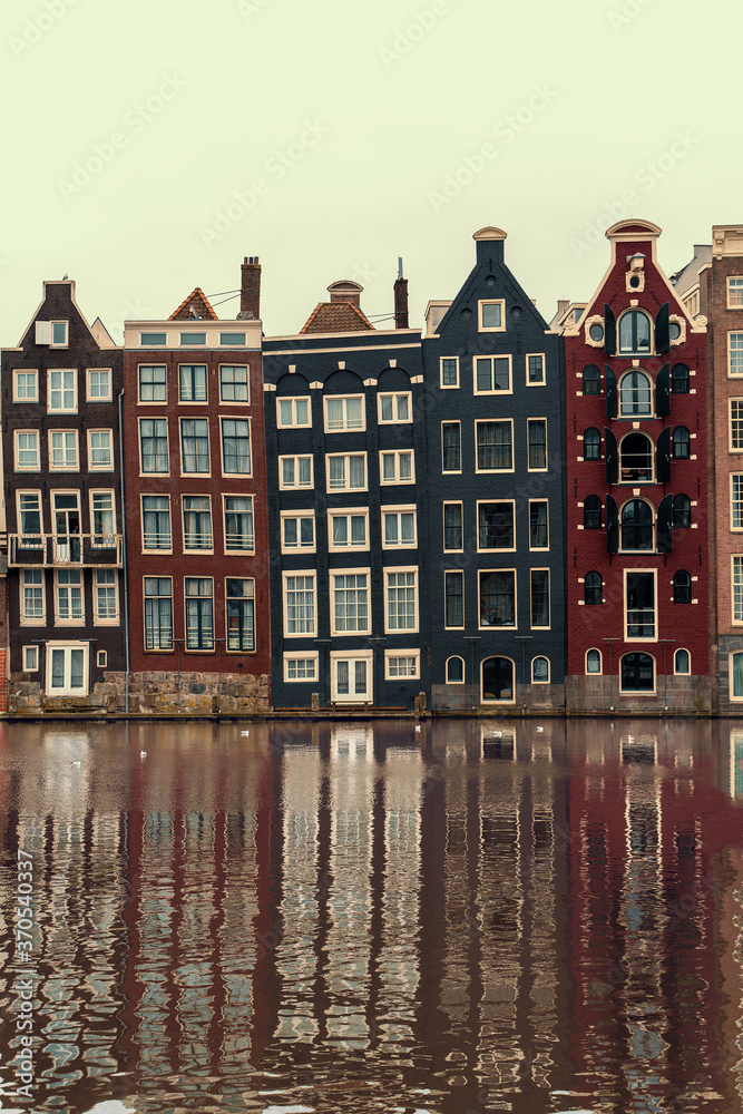 Amsterdam, Netherlands, famous dancing houses with reflection in river Amstel, vertical image.