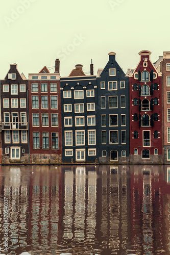 Amsterdam, Netherlands, famous dancing houses with reflection in river Amstel, vertical image.