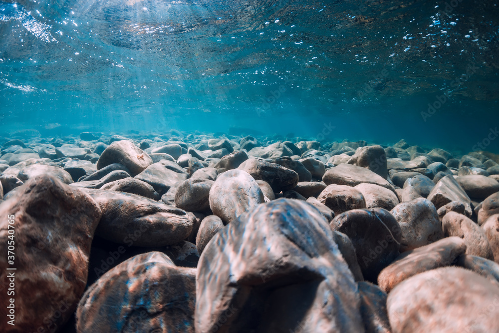 Underwater view with stones and blue transparent water.