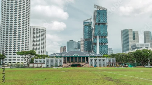 Skyline with Singapore Recreation Club and skycrapers on background timelapse hyperlapse. Green lawn and clouds on a the sky photo