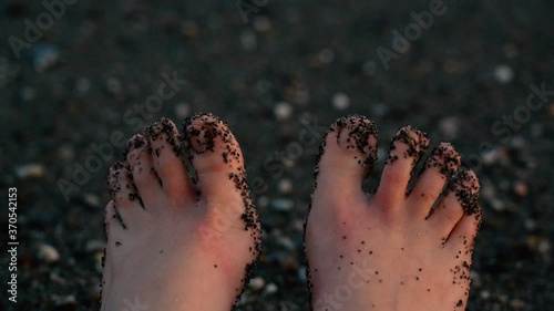 Woman toes full of sand moving happily at the beach photo