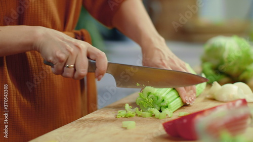 Woman hands chopping celery on cutting board. Housewife cooking fresh vegetables