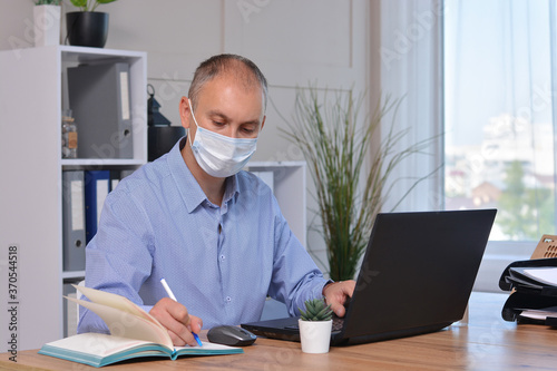 Businessman works in the office in a medical mask for coronavirus protection. New normal business practise of coronavirus covid-19 outbreak control