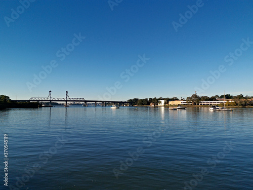 Beautiful view of high-rise buildings on the riverbank on a sunny day with deep blue sky, Parramatta river, Meadowbank, Sydney, New South Wales, Australia © Ivan