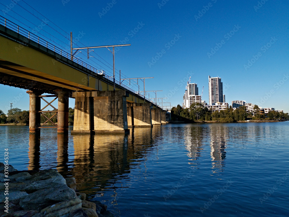 Beautiful view of a railway bridge across a river on a sunny day with deep blue sky, Parramatta river, Meadowbank, Sydney, New South Wales, Australia