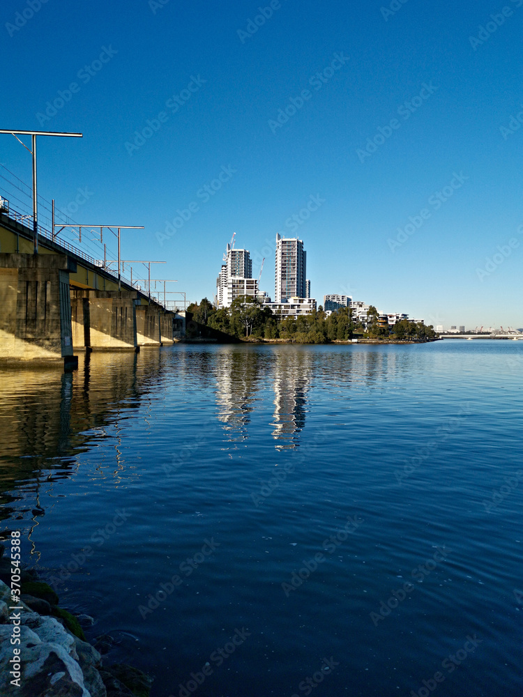 Fototapeta premium Beautiful view of a railway bridge across a river on a sunny day with deep blue sky, Parramatta river, Meadowbank, Sydney, New South Wales, Australia