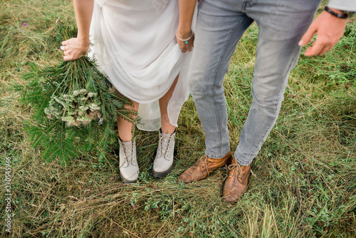Beautiful bride and groom. close-up wedding shoes. bride with flowers in mountains, beautiful nature, landscape, sunset