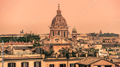 Rome skyline with old colorful houses and rooftop terraces on sunny day. Dome of San Carlo al Corso basilica on the background. Rome, Italy