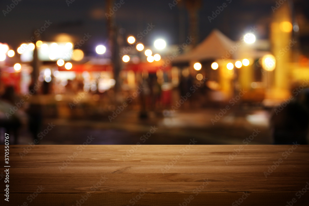 background Image of wooden table in front of abstract blurred restaurant lights