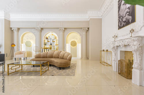 chic luxury interior in an old antique style open-plan apartment decorated with columns and stucco on the wall in pastel colors. tiles on the floor. beige walls