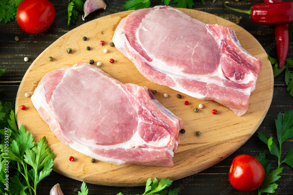 Fresh raw pork entrecote on the bone, a piece of pork with spices on a wooden board