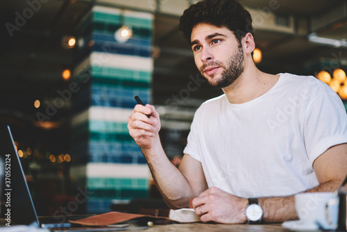 Cuadro en lienzo Talented young student hipster guy dressed in casual white t shirt looking out o