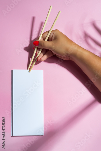 Woman's hand holds brochure by wooden sticks.