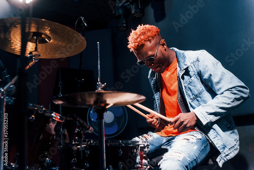 Plays drums. Young african american performer rehearsing in a recording studio